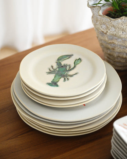 Stack of ceramic plates with a lobster design on a wooden surface
