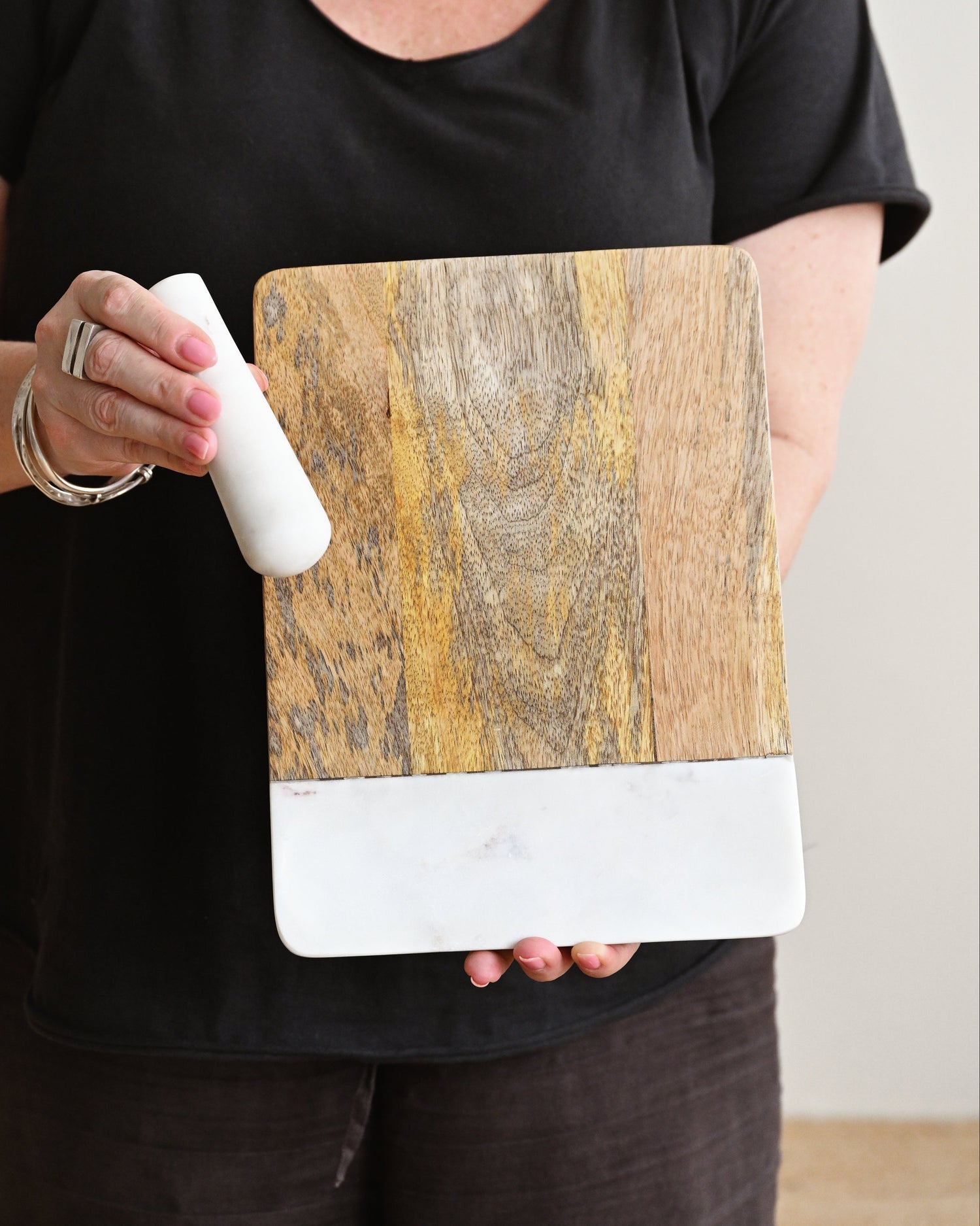 Person holding a wooden and white rectangular object against a plain background