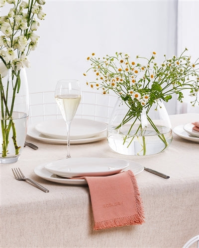 Elegant table setting with pink napkins, white plates, and floral arrangements.