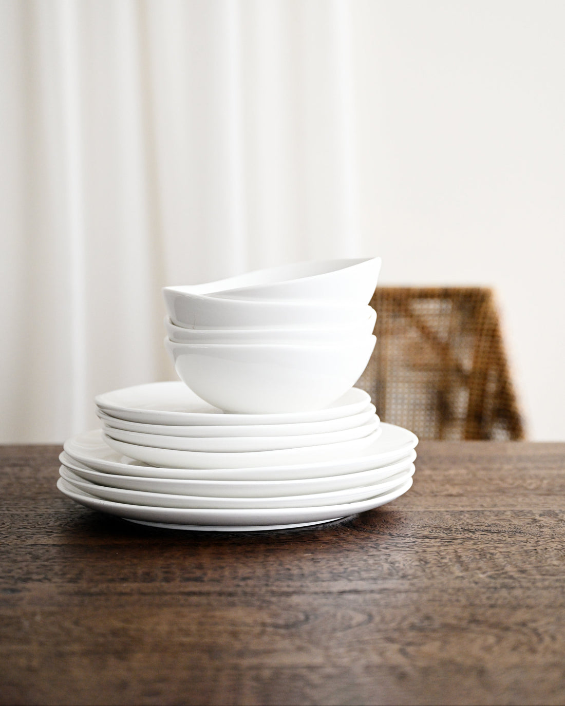 Stack of white ceramic bowls on a wooden table with a blurred background