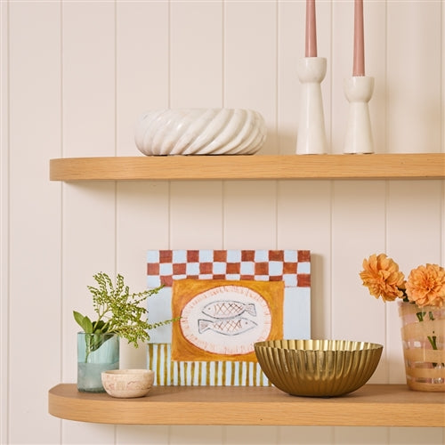 Wooden shelves with decorative items including a gold bowl, plant, and framed picture against a light wall.