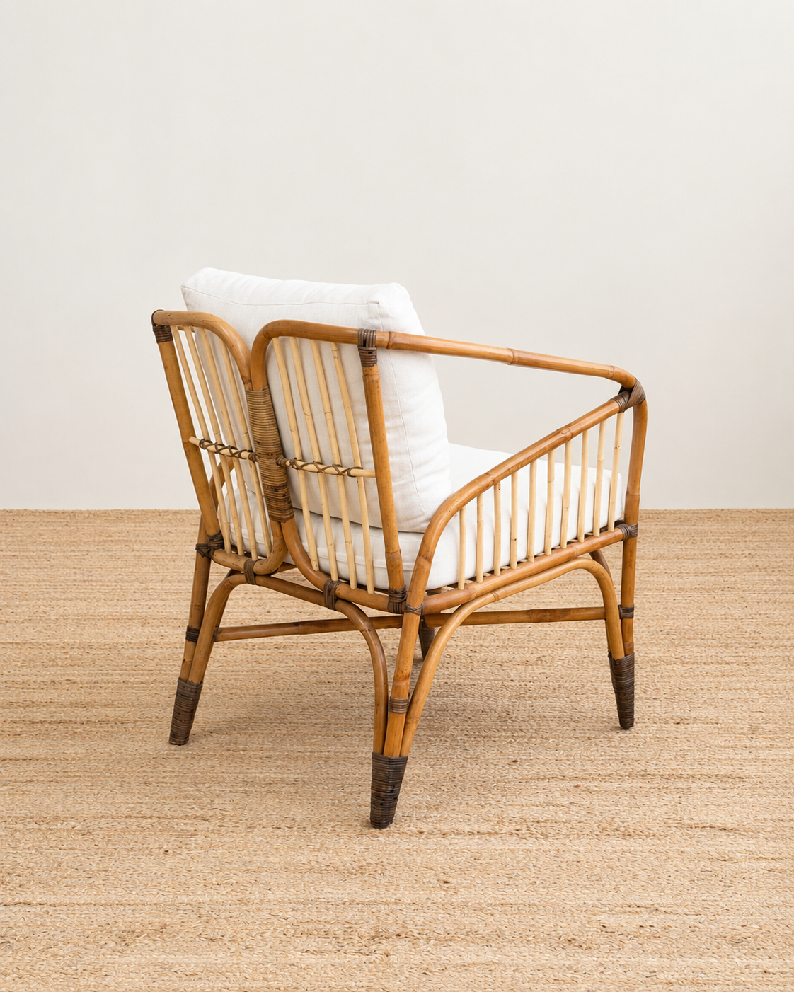 Rattan armchair with white cushion on a wooden floor and light-colored wall background