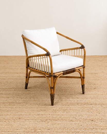 Rattan armchair with white cushion on a beige carpet