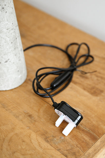 Black electrical cord with UK plug on a wooden surface
