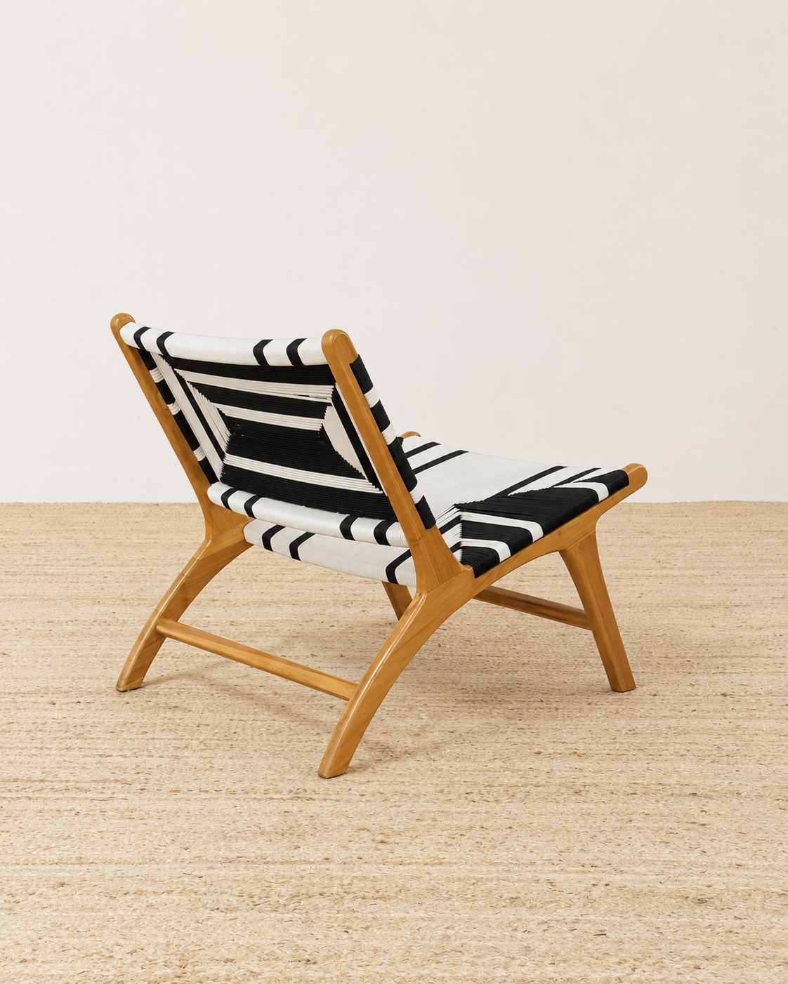 Wooden chair with a black and white striped cushion on a light wooden floor.