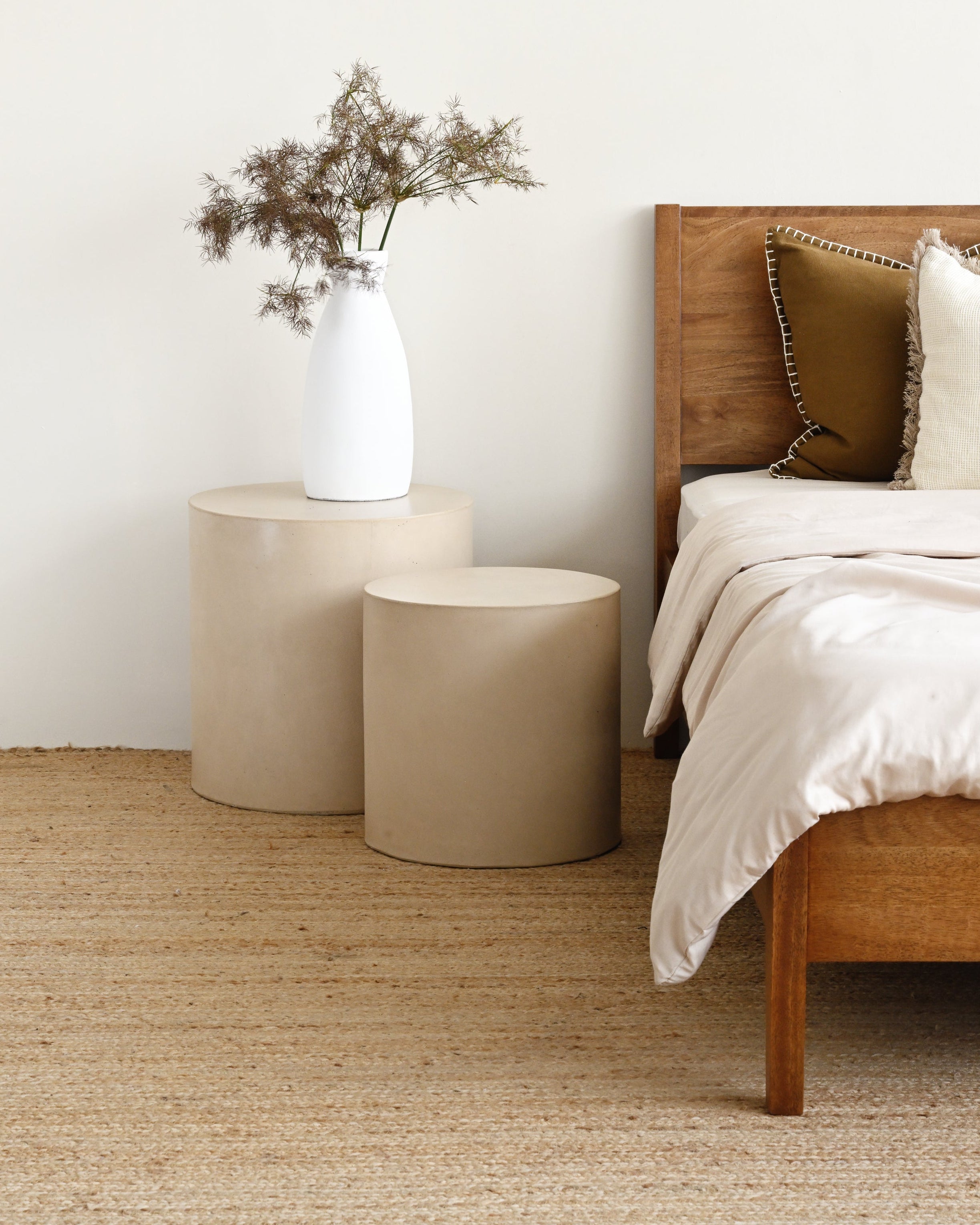 Bedroom with wooden bed, beige rug, and side tables.