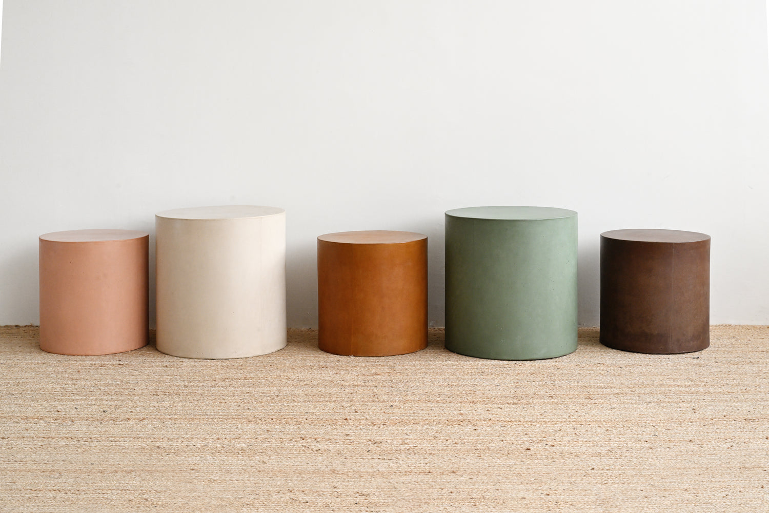 Five cylindrical containers in different colors lined up on a textured surface with a white background