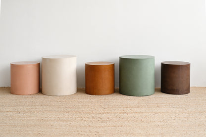 Five cylindrical containers in different colors lined up on a textured surface with a white background
