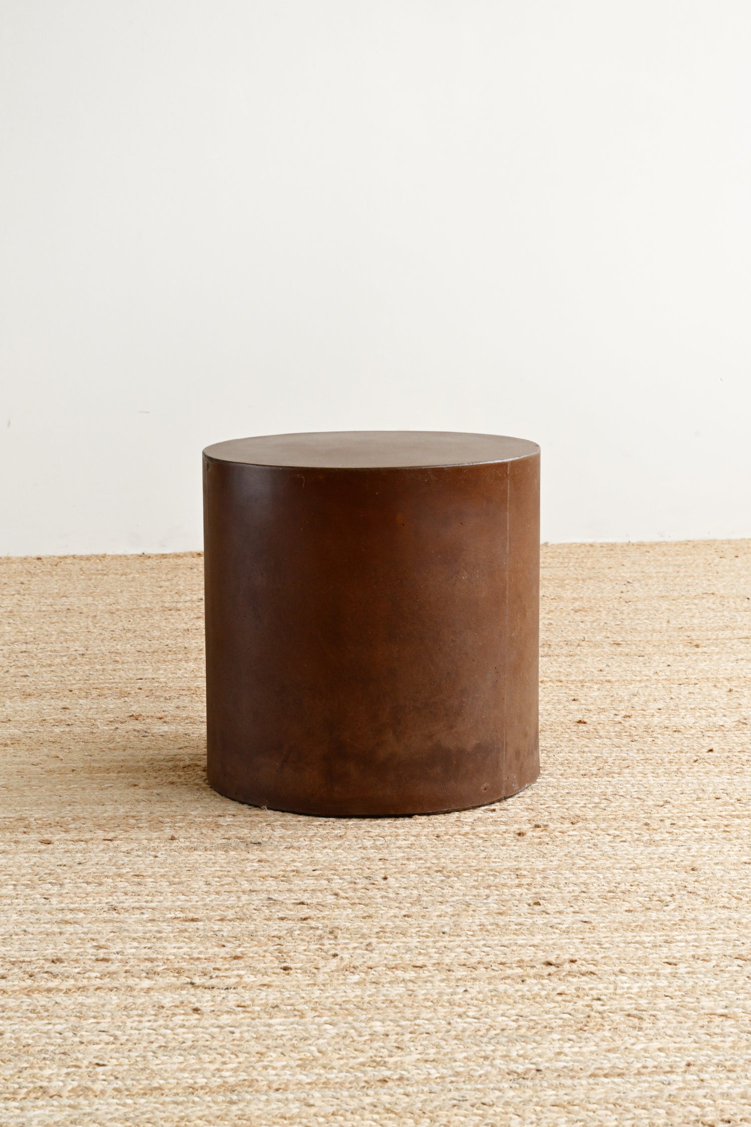 Brown cylindrical stool on a textured surface with a neutral background