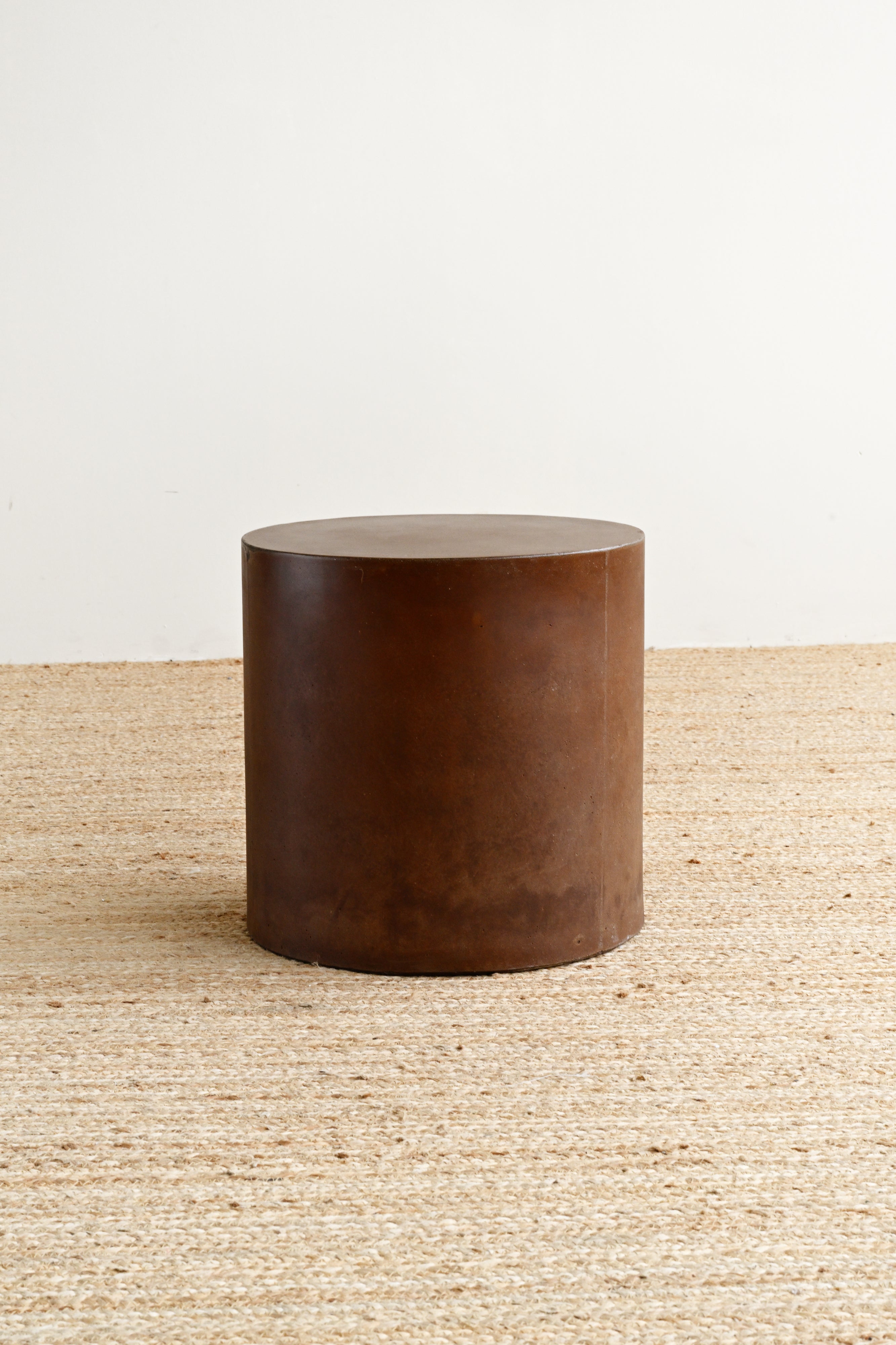 Brown cylindrical stool on a textured surface with a neutral background