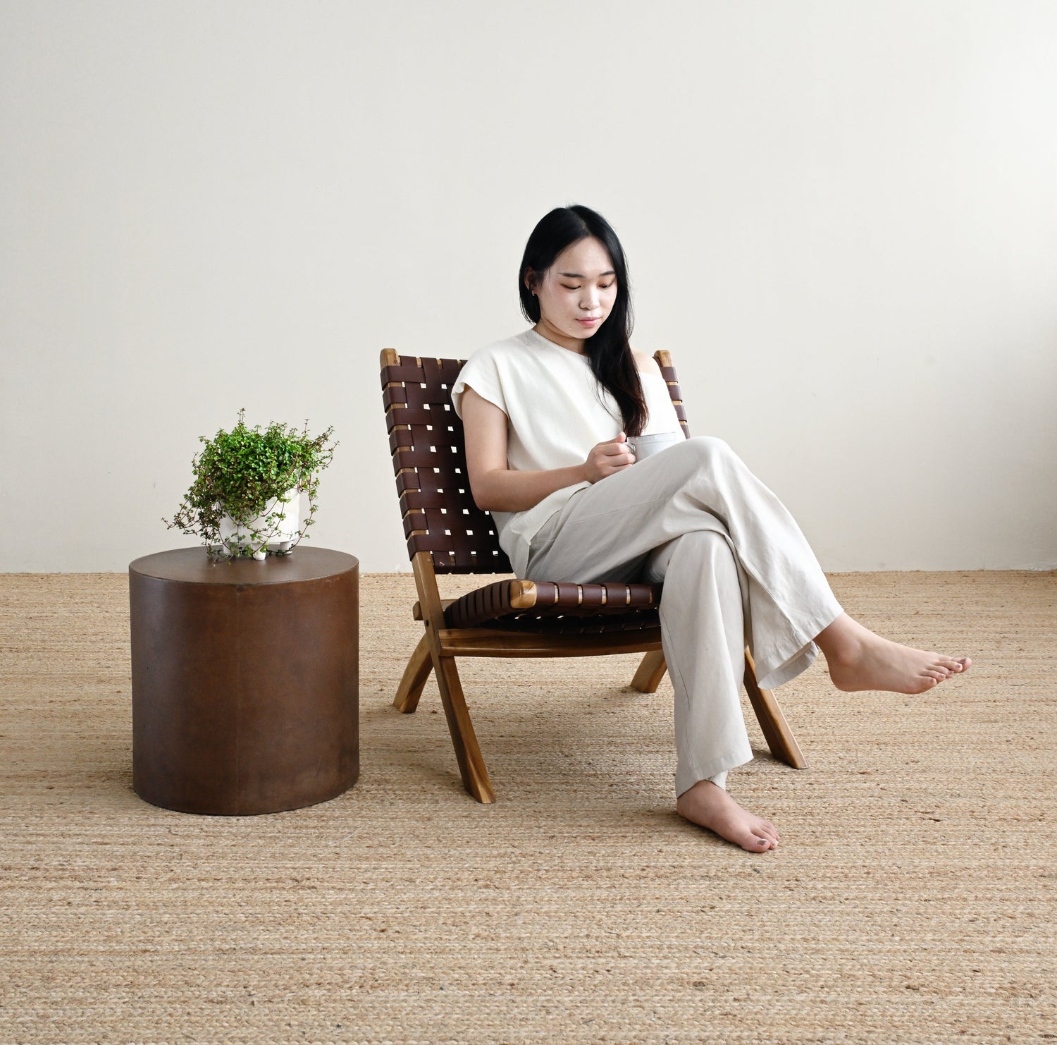 Woman sitting on a chair in a room with a textured floor and a small table with a plant.
