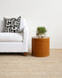 Modern living room with a white sofa, patterned pillow, and wooden side table.