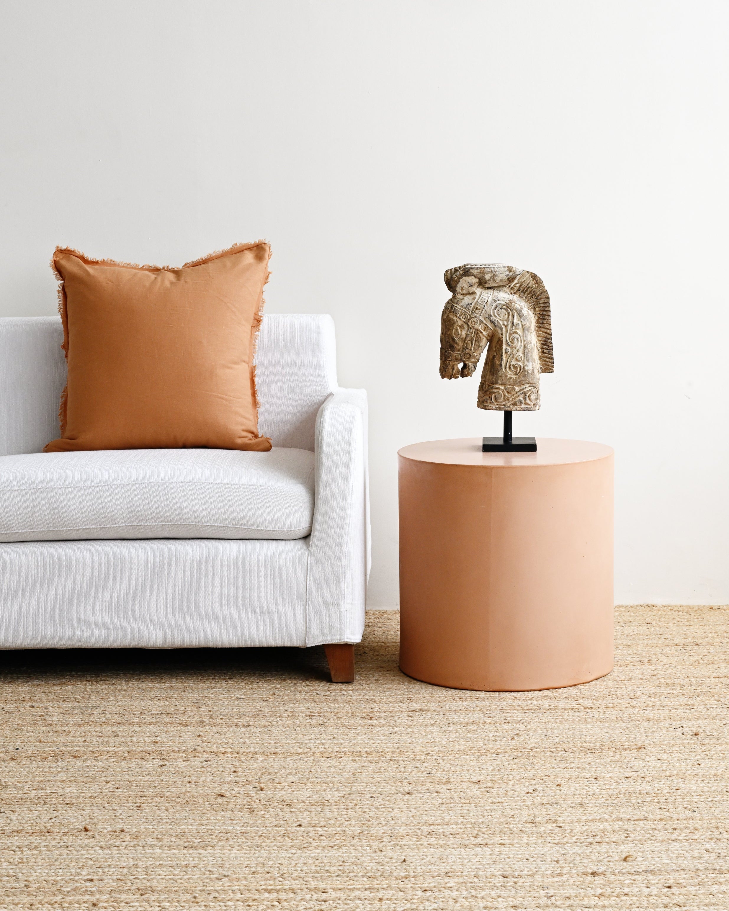 Living room with a white sofa, brown pillow, and a small round table with a decorative item.