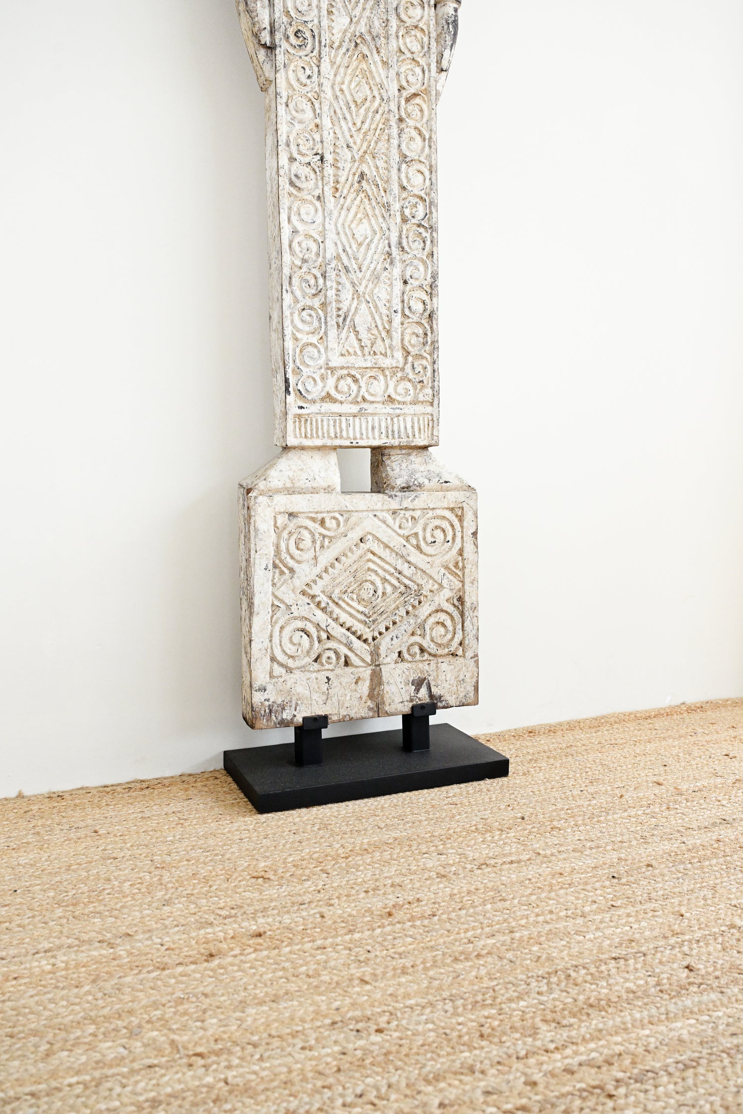 Decorative stone column on a stand against a white wall