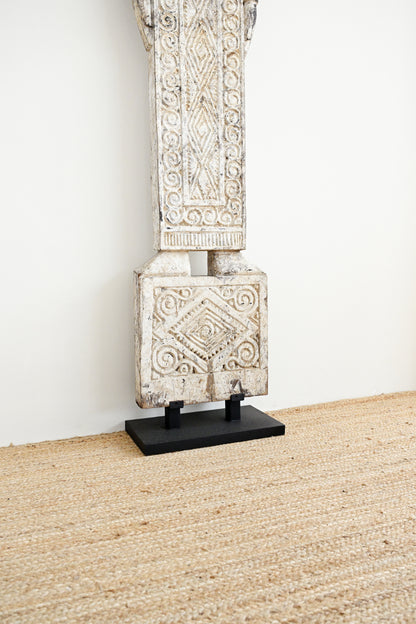 Decorative stone column on a stand against a white wall