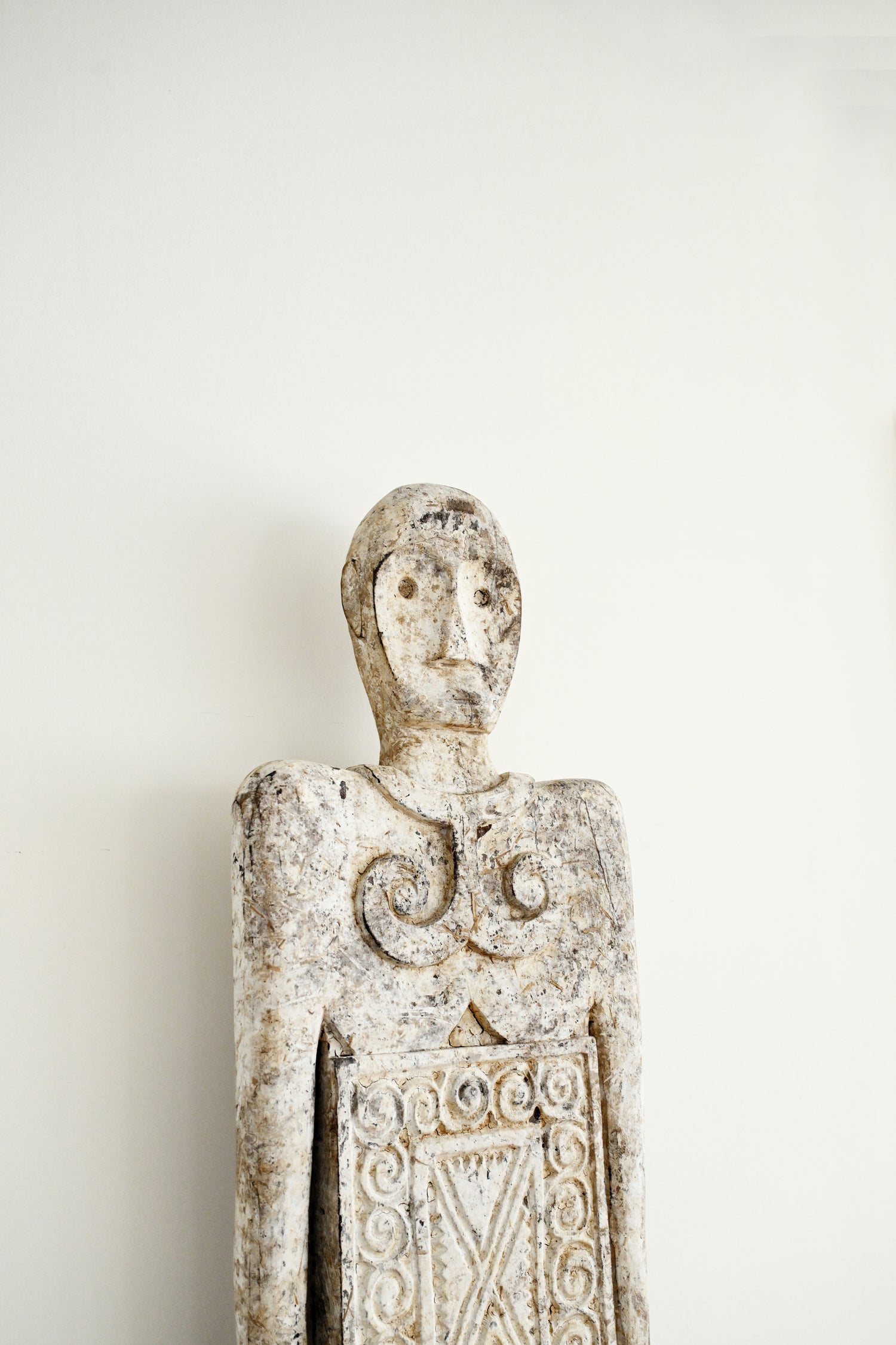 Decorative stone figure with intricate carvings on a plain background