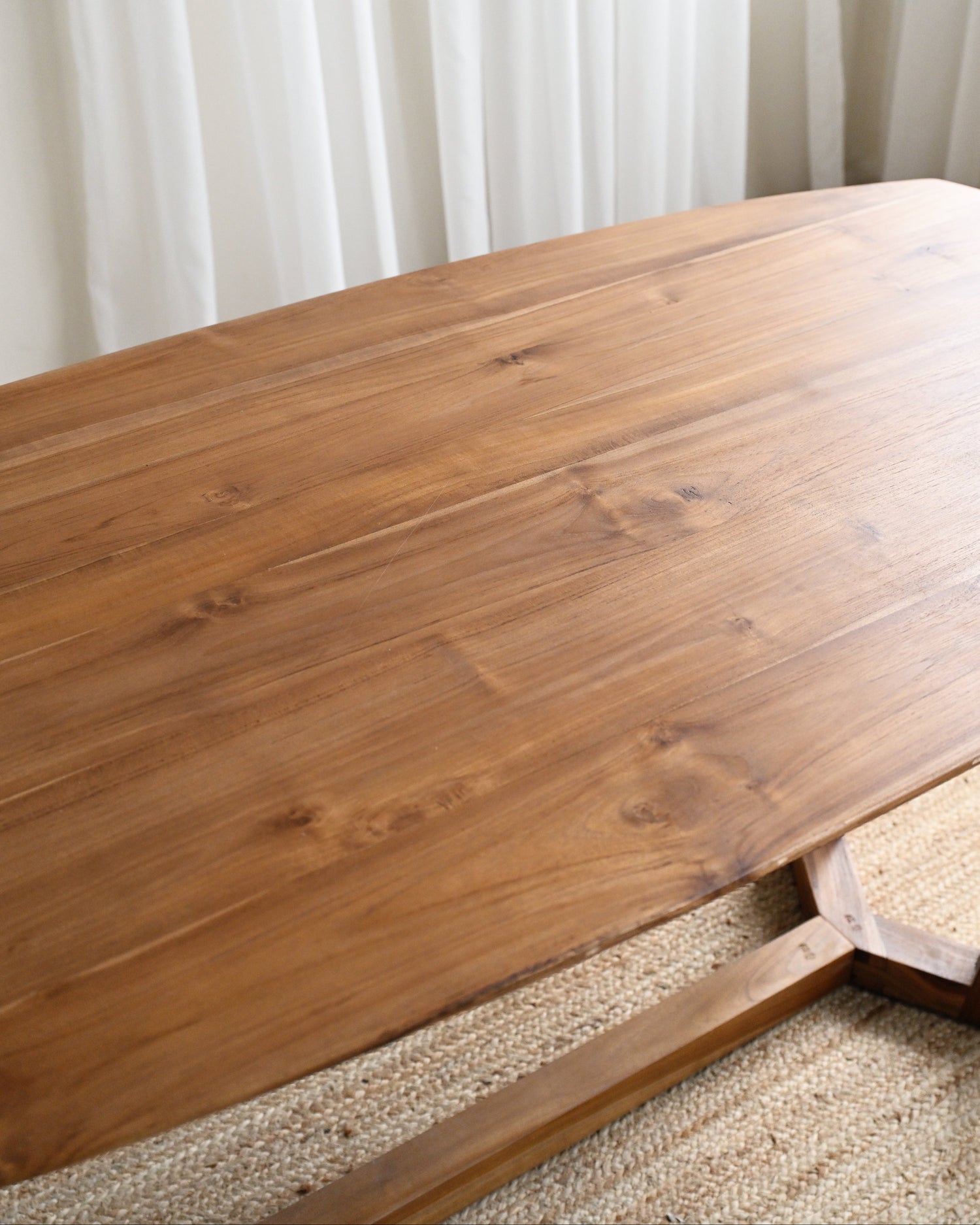 Wooden table with a textured surface against a white curtain background