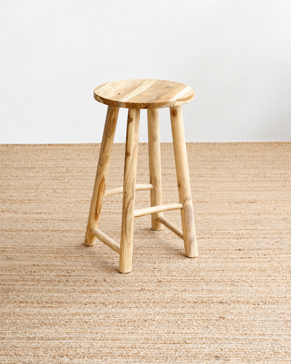 Wooden stool on a textured beige floor with a light gray wall background