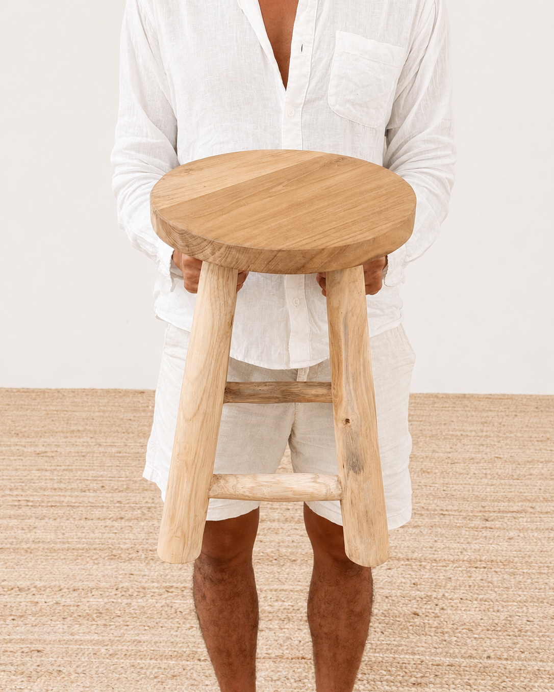 Person holding a wooden stool on a neutral background