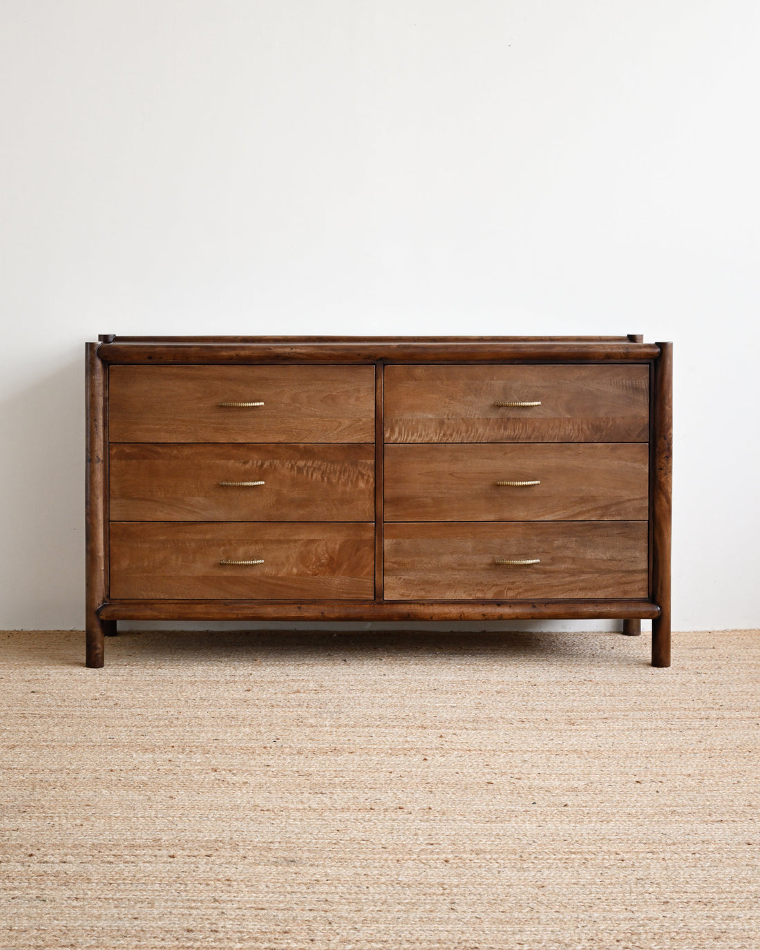 Wooden dresser with four drawers on a beige carpet and white wall background