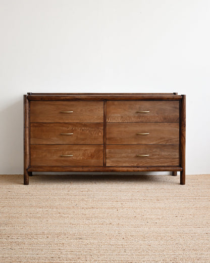 Wooden dresser with four drawers on a beige carpet and white wall background