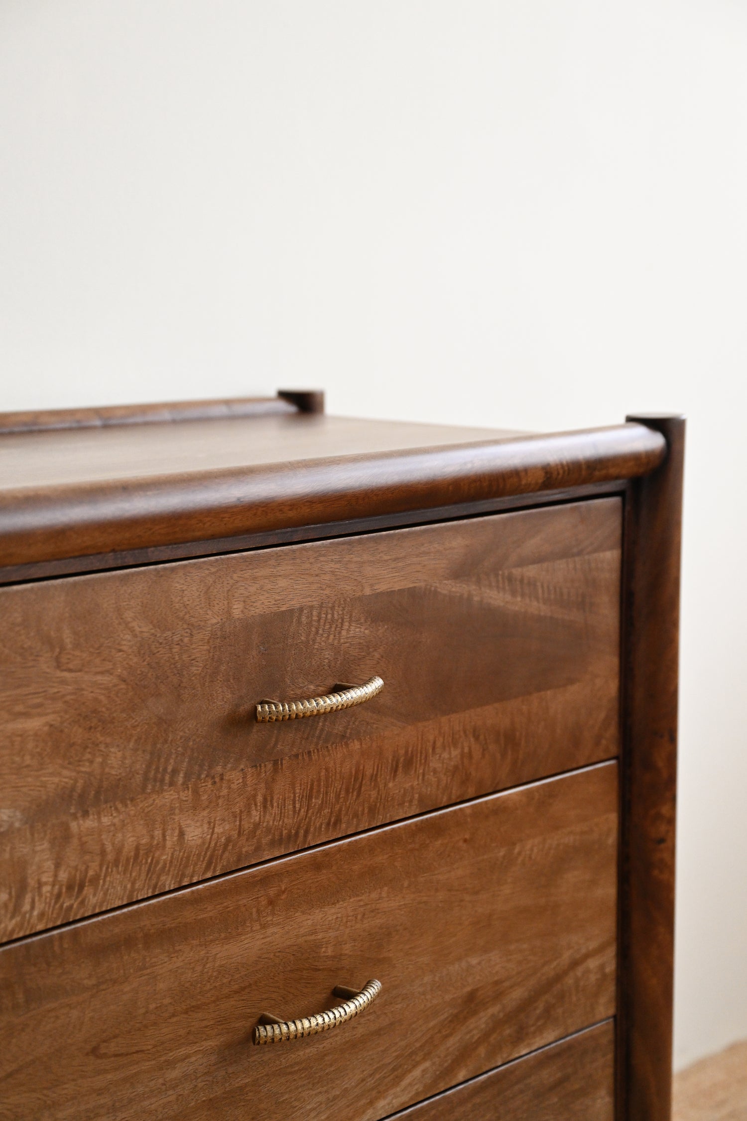 Wooden dresser with two drawers and brass handles on a plain background