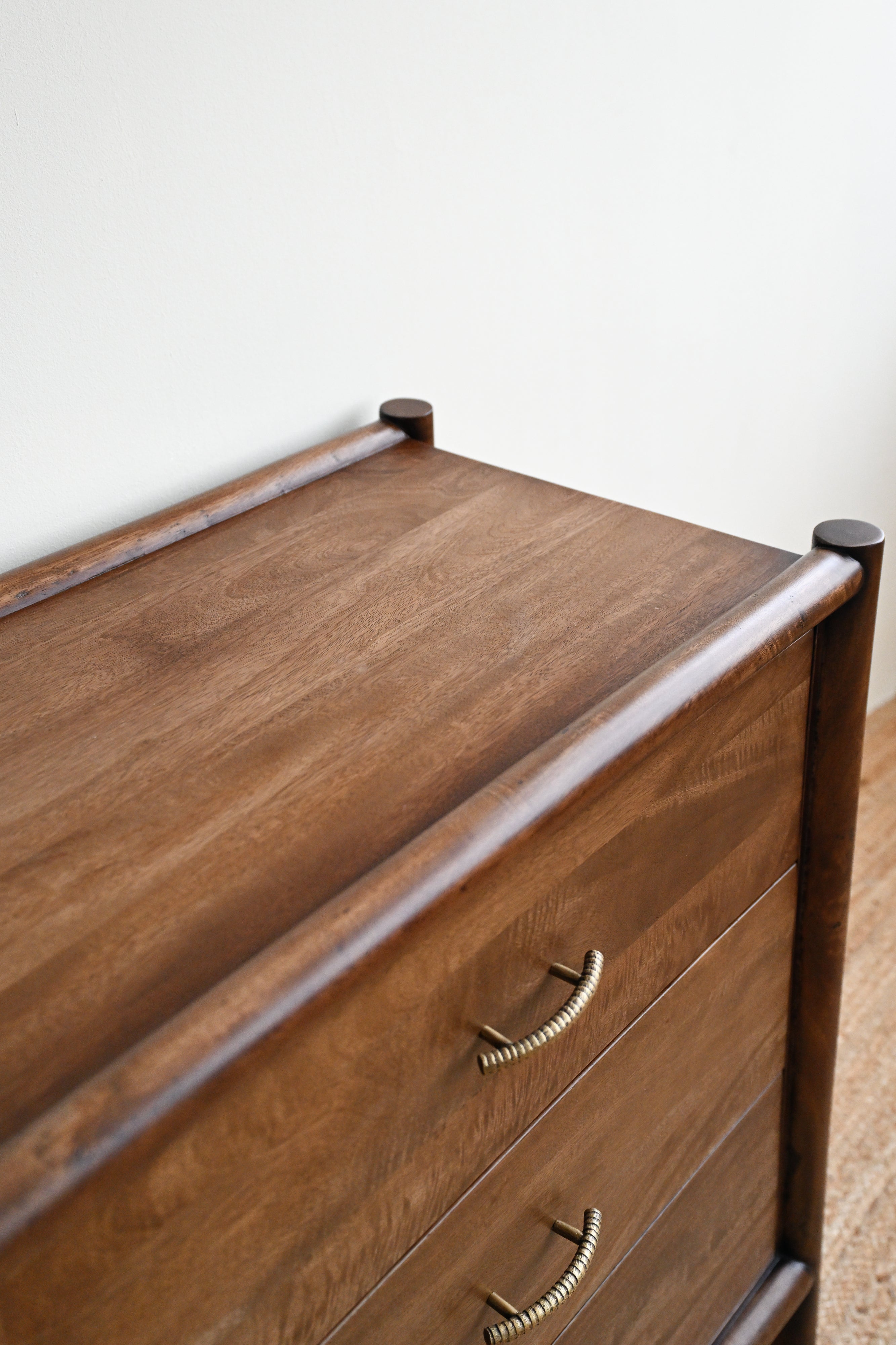 Wooden dresser with three drawers against a white wall