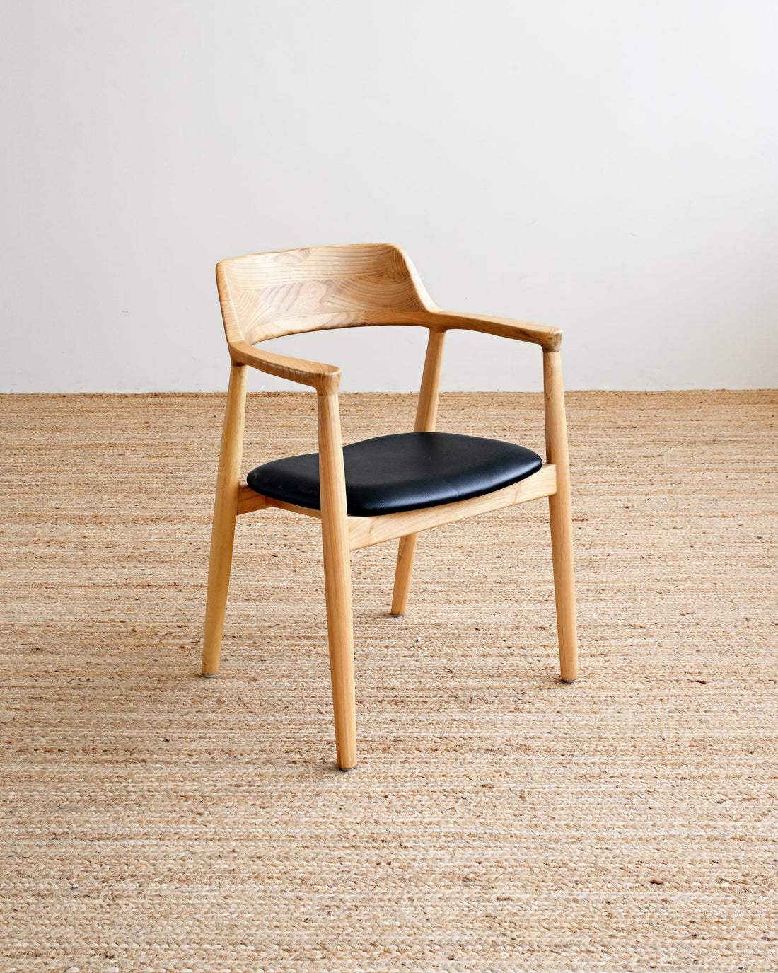 Wooden chair with a black seat on a beige carpet