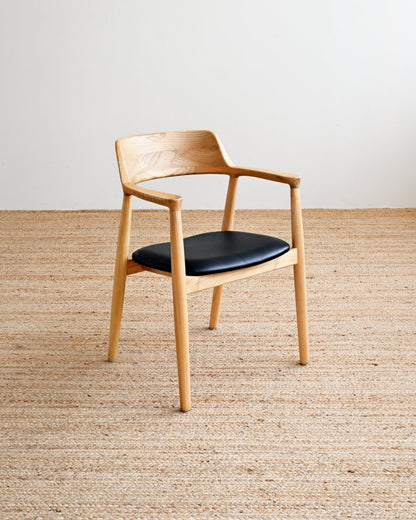 Wooden chair with a black seat on a beige carpet