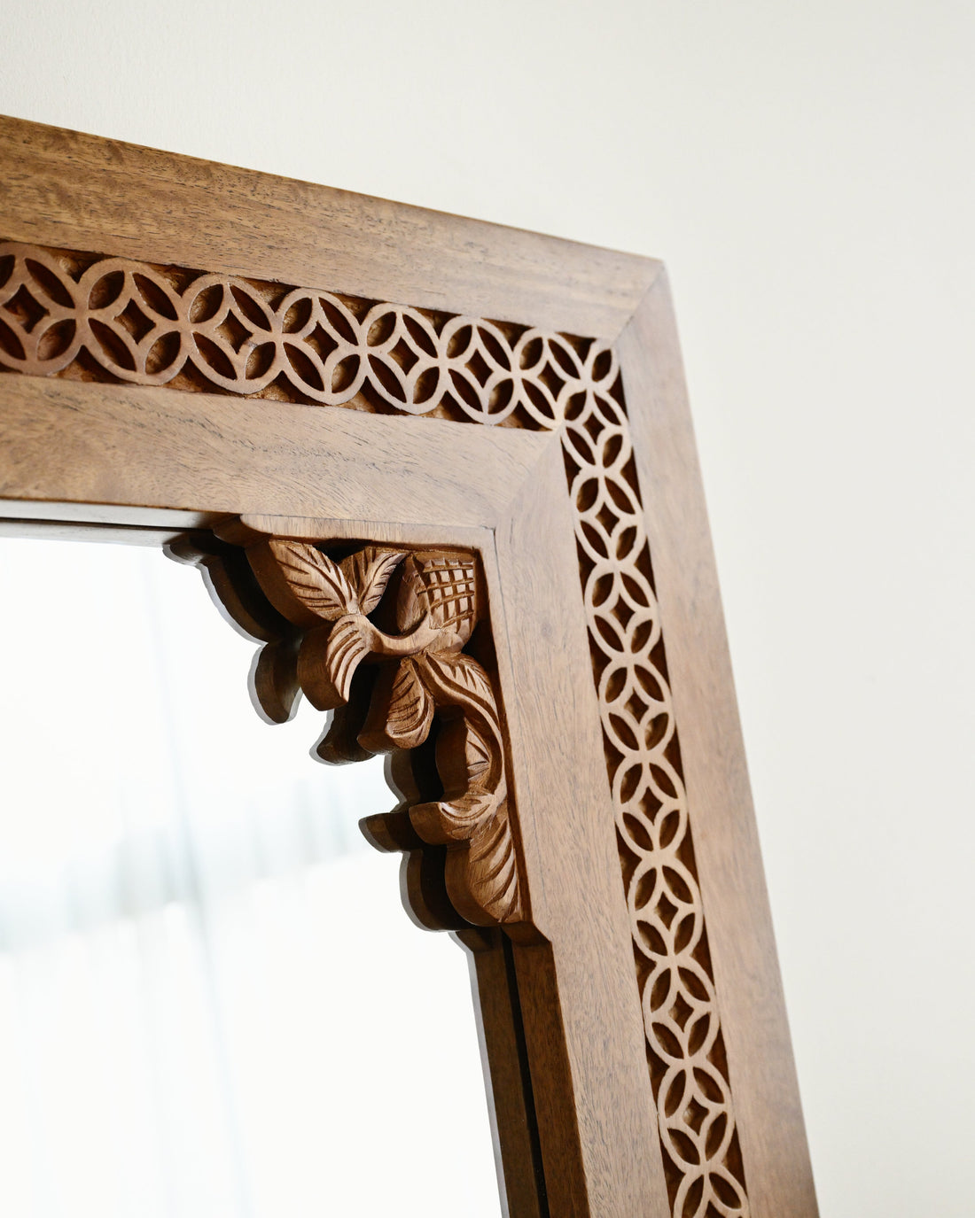 Wooden mirror frame with intricate carvings on a white background