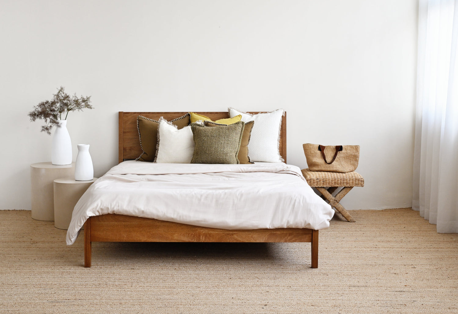 Wooden bed with white bedding and pillows in a minimalistic bedroom.
