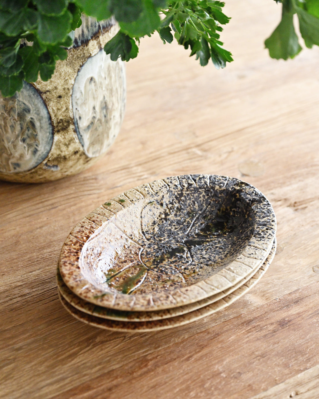 Stack of ceramic bowls on a wooden surface with greenery in the background
