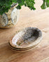 Stack of ceramic bowls on a wooden surface with greenery in the background