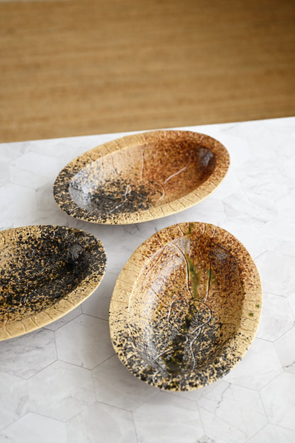 Three ceramic bowls with speckled glaze on a light surface