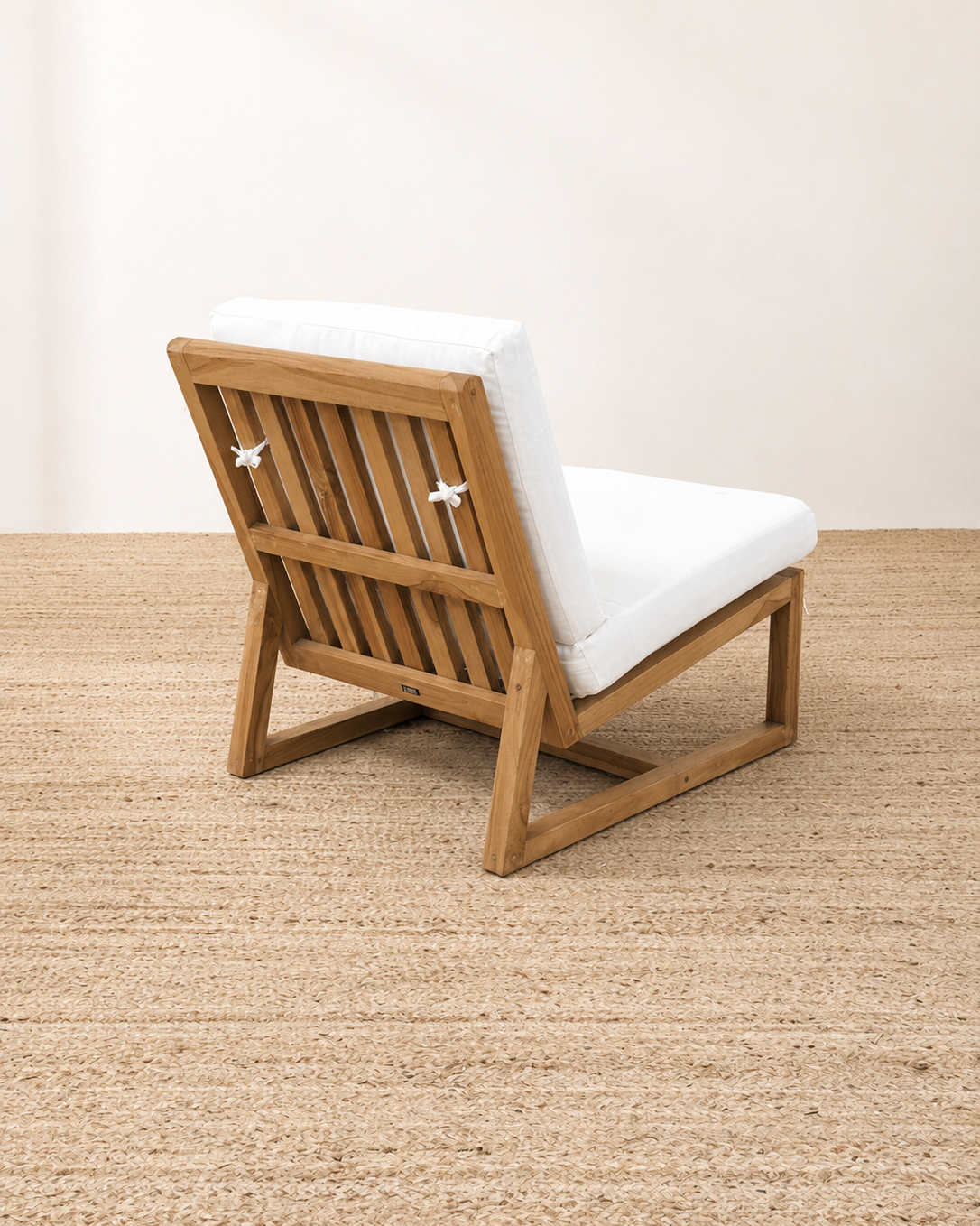 Wooden chair with white cushions on a textured floor
