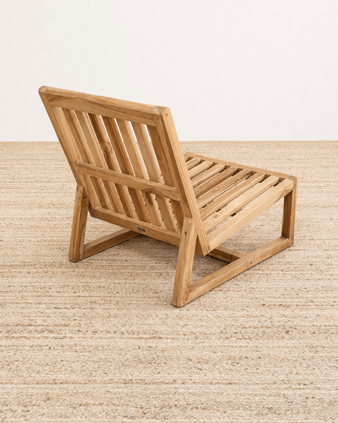Wooden lounge chair on a textured beige surface with a neutral background