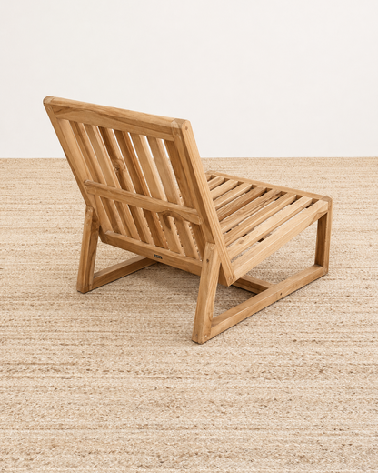 Wooden lounge chair on a textured beige surface with a neutral background