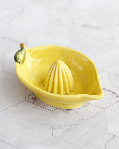 Yellow lemon-shaped citrus juicer on a marble surface