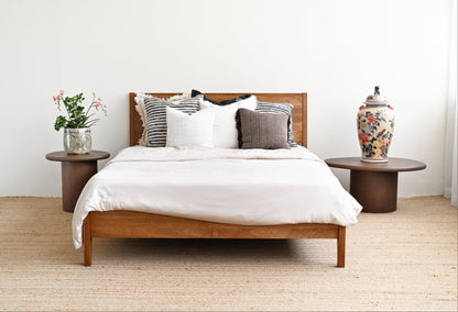 Wooden bed with white bedding and decorative pillows in a bedroom setting.