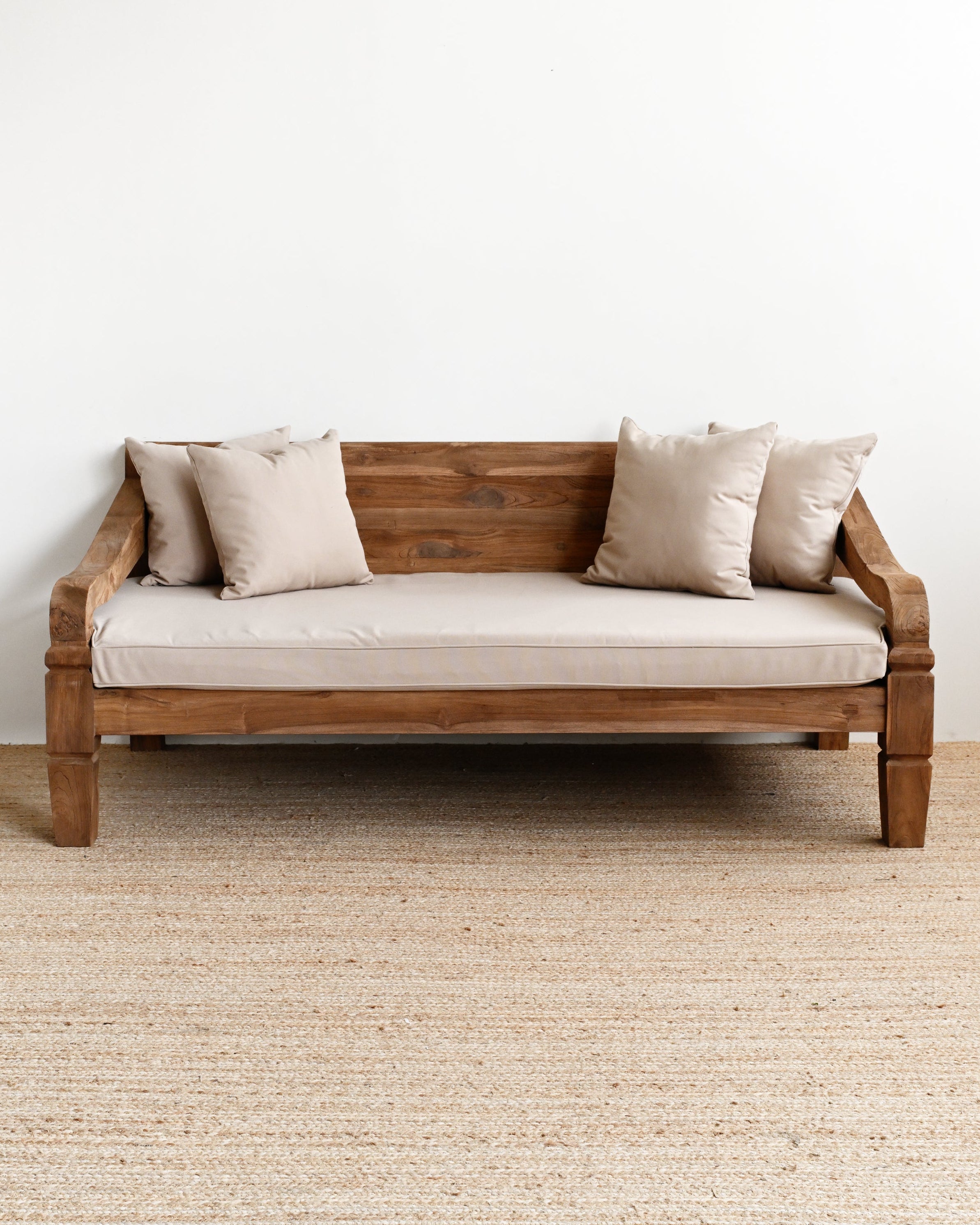 Wooden sofa with beige cushions on a plain white wall background