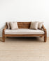 Wooden sofa with beige cushions on a plain white wall background