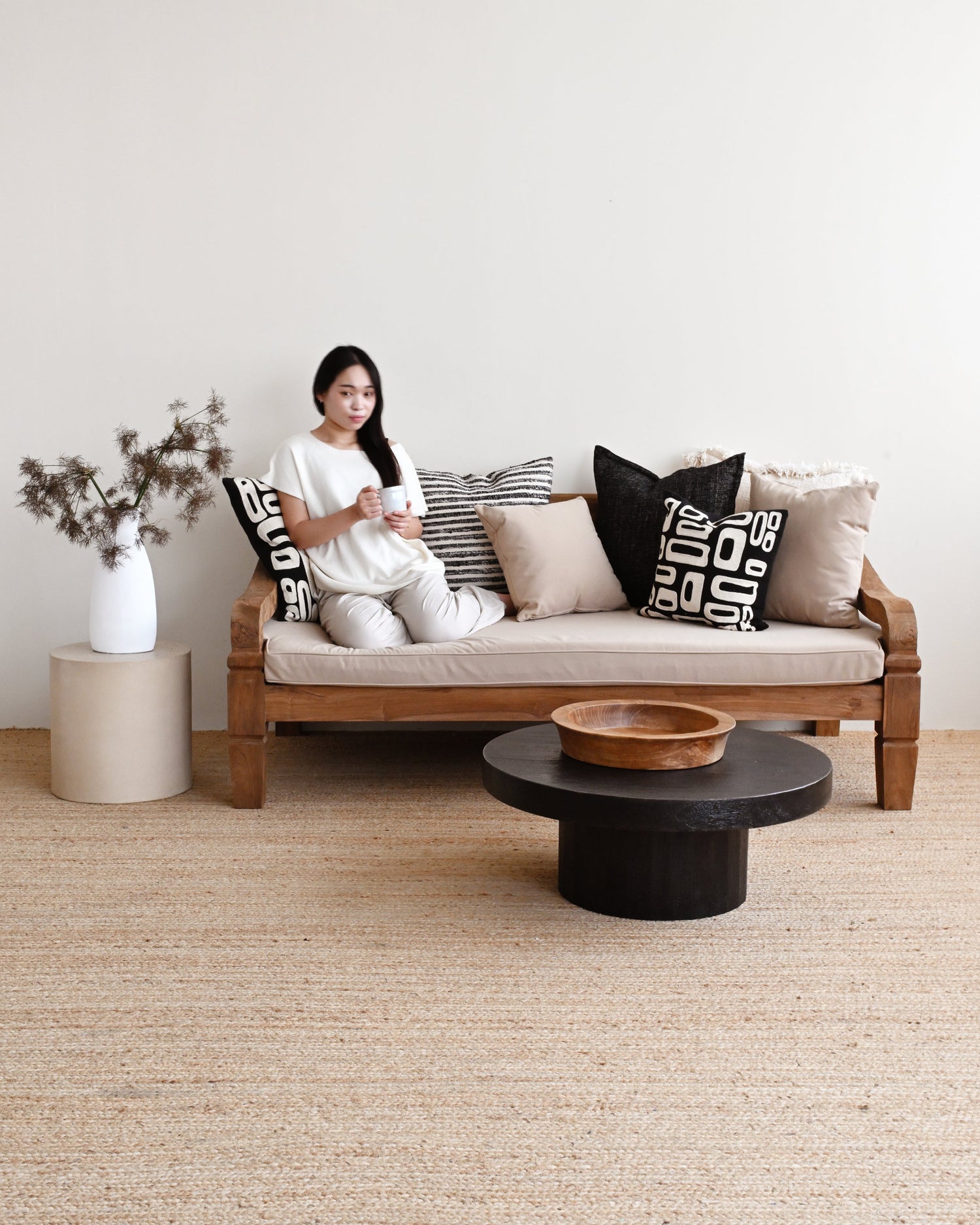 Woman sitting on a couch with decorative pillows in a minimalistic living room.