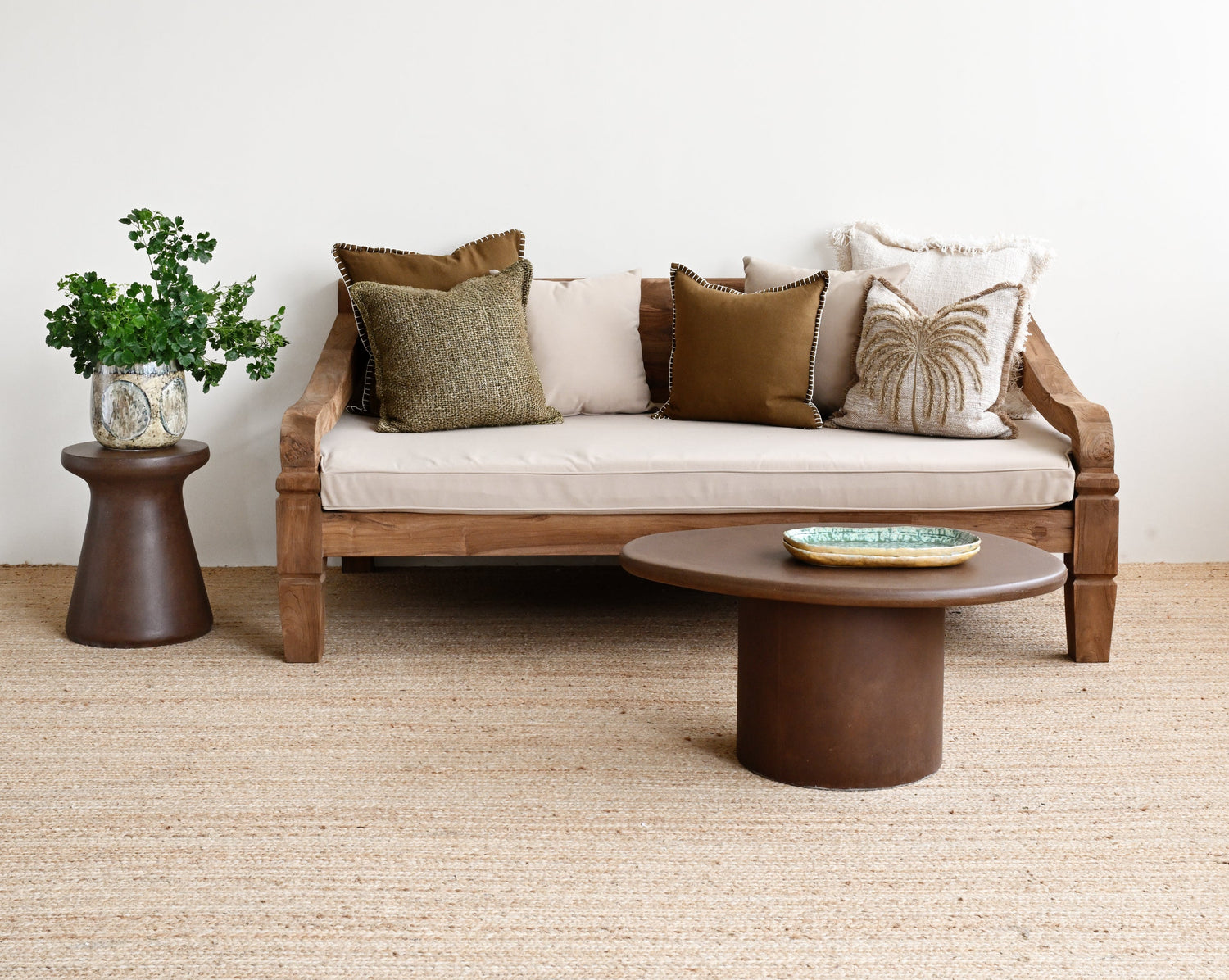 Modern living room with a wooden sofa, round coffee table, and decorative pillows on a light-colored carpet.