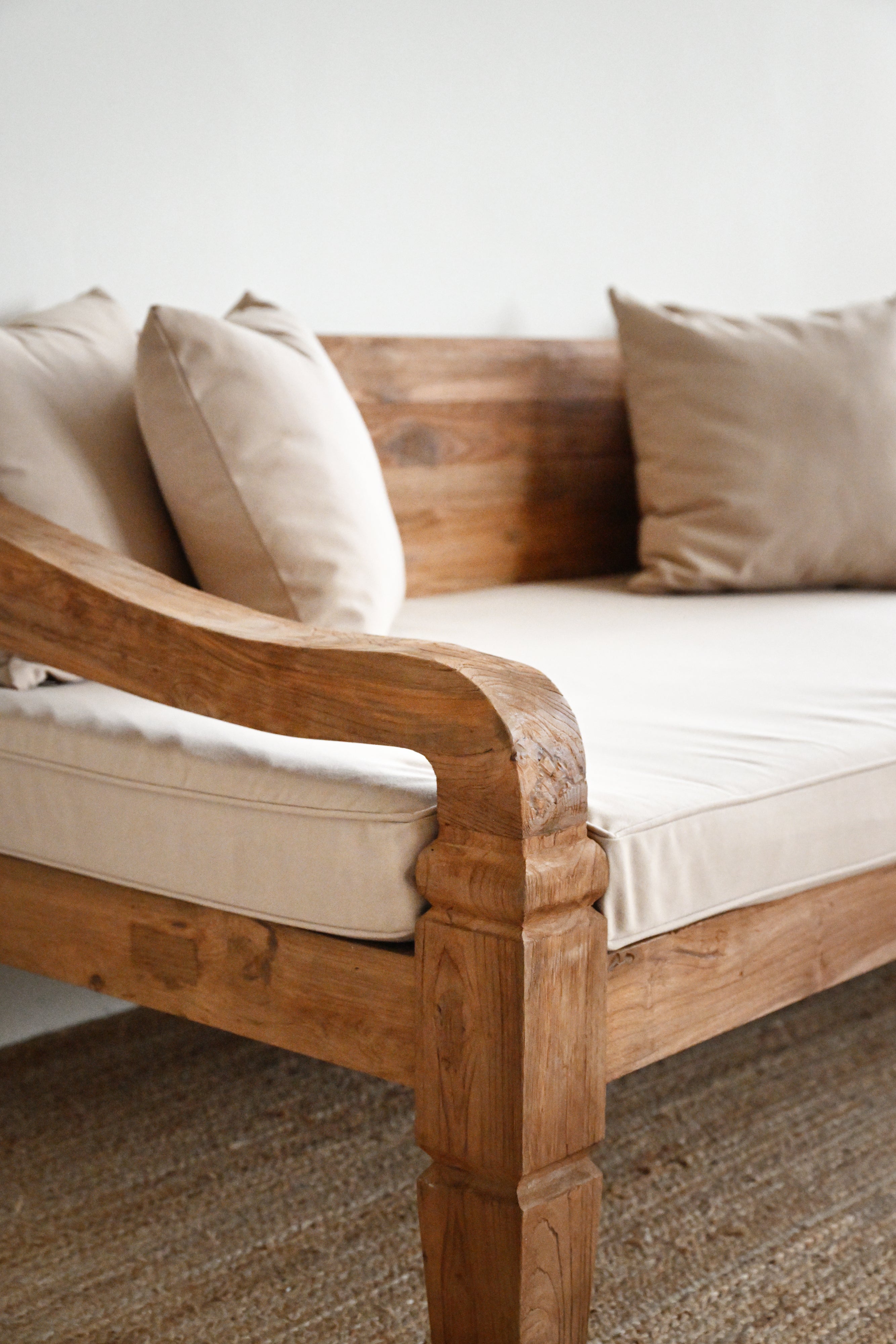 Wooden sofa with beige cushions on a neutral background
