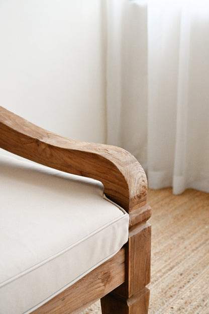 Wooden chair with beige cushion against a white curtain background