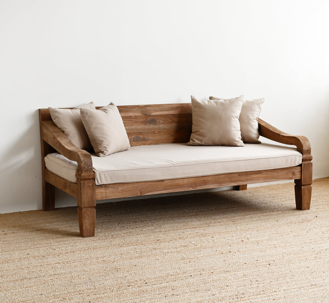 Wooden sofa with beige cushions on a textured floor and white wall background