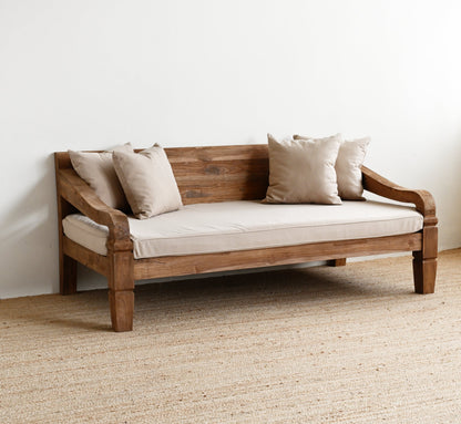 Wooden sofa with beige cushions on a textured floor and white wall background
