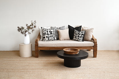 Wooden sofa with patterned cushions in a minimalistic living room.