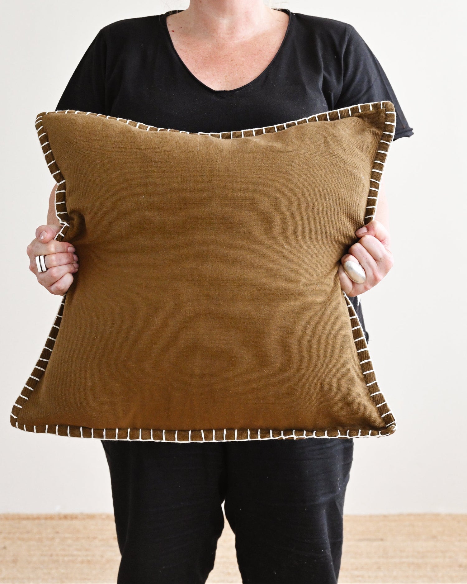 Person holding a brown pillow with a plain background