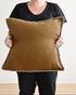 Person holding a brown pillow with a plain background